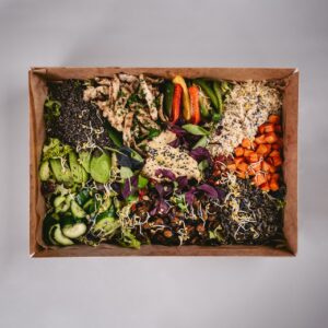 Das Bild zeigt eine Box für eine Bowl mit Chicken und Karotten und Avocado und mehr.